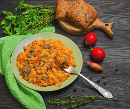 Vegetarian lunch stewed braised cabbage with mushrooms, carrots. Herbs spices for cabbage stewed with mushrooms parsley, thyme, pepper, cherry tomatoes, onions, grain bread. Stewed cabbage on forkの写真素材