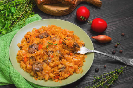Vegetarian lunch stewed braised cabbage with mushrooms, carrots. Herbs spices for cabbage stewed with mushrooms parsley, thyme, pepper, cherry tomatoes, onions, grain bread. Stewed cabbage on forkの写真素材