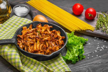 Raw not cooked Pasta spaghetti Tagliatelle with mushrooms chanterelles. Mushrooms, chanterelles pasta. Ingredients for pasta spaghetti mushrooms tomatoes, thyme, lettuce, oil. Dark wooden background.の写真素材