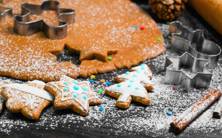 Cooking Christmas cookies gingerbread. On a dark brown background gingerbread dough. Forms for Christmas cookies gingerbread, rolling pin, cones. Cookies with icing. Christmas New Year card.の写真素材