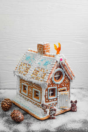 New Year Christmas gingerbread house decorated with icing sugar snow. Christmas figure Santa Claus, reindeer, snowman next to gingerbread house. Christmas rooster symbol of new year gingerbread house.の写真素材
