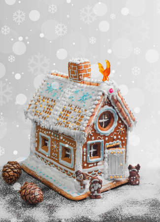 New Year Christmas gingerbread house decorated with icing sugar snow. Christmas figure Santa Claus, reindeer, snowman next to gingerbread house. Christmas rooster symbol of new year gingerbread house. Isolated on whiteの写真素材