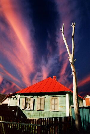 Abandoned green wooden house with red roof opon dramatic skyの写真素材