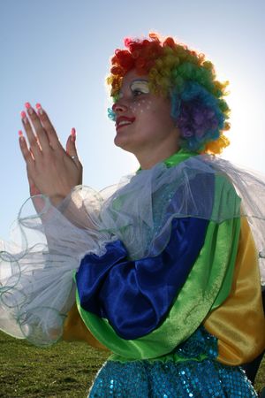Expressive bizzare clown in colored wig upon blue skyの写真素材