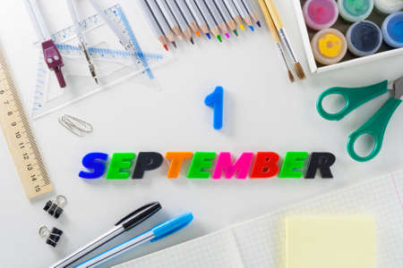 The word 1 September from multi-colored plastic letters on a white background with school articles.