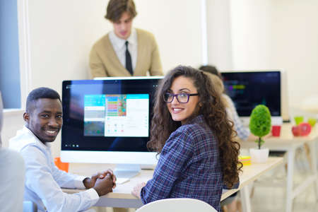 Group of entrepreneurs working using a laptop and holding a document