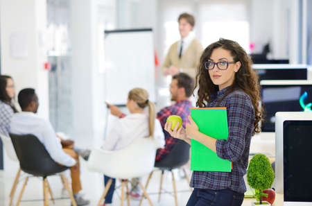 business, startup and people concept - happy creative team with computer and folder in officeの写真素材