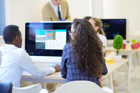 Group of entrepreneurs working using a laptop and holding a document