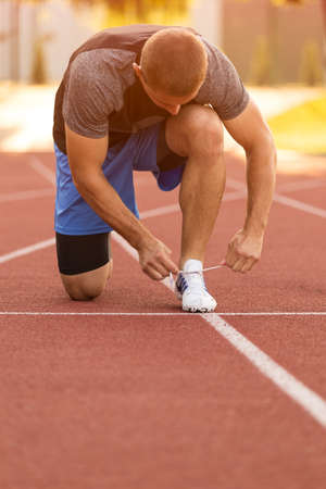 Female athlete tying laces for jogging. Woman jogging on a running track. running shoes. Fitness...