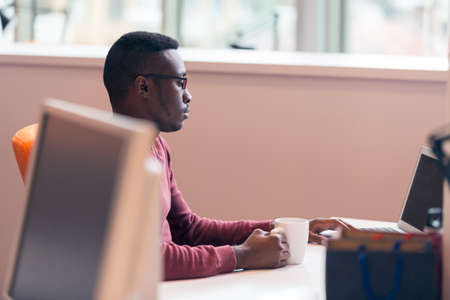 Handsome successful African American looking at the screen with serious face expression at modern...