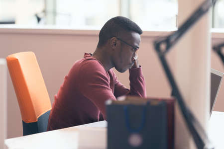 Handsome successful African American looking at the screen with serious face expression at modern...