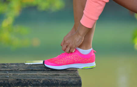 Runner girl tying laces shoes at the bench.