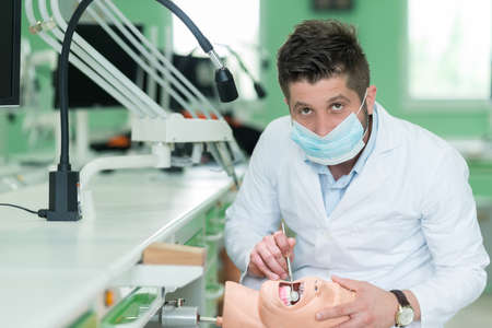 Male dental student practicing on doll