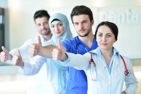 healthcare and medicine concept - attractive male doctor in front of medical group in hospital...