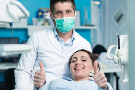 Dentist examining Patient teeth with a Mouth Mirror. Dentist is a Man, Patient is a Woman. Patient is Relaxed and not scared of Dentist.の写真素材