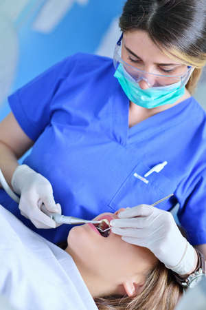 A pretty young woman with a bright, white smile lying in the dentist's chair having a checkupの写真素材