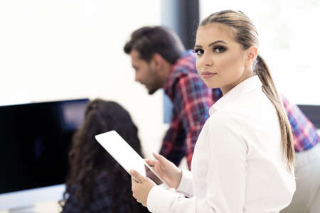 Smiling young women using digital tablet in the officeの写真素材