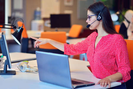 Young woman working in call centre, surrounded by colleagues