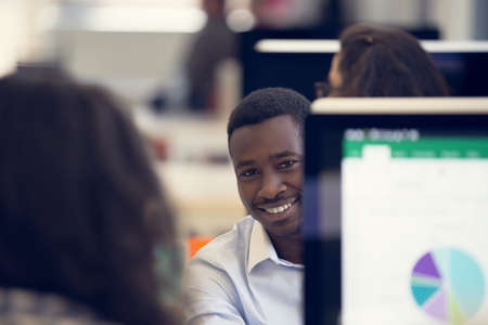 Portrait of a happy African American entrepreneur displaying computer laptop in office.の写真素材
