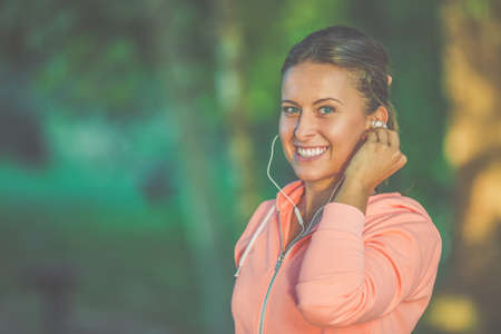 Beautiful woman during fitness at park is listening music.の写真素材
