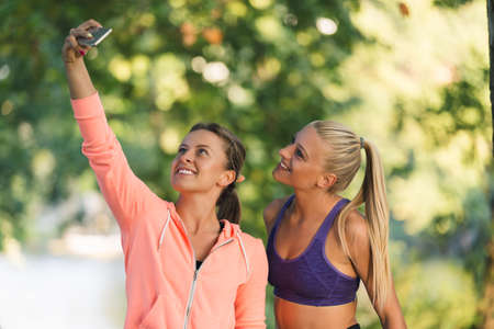 Beautiful girls taking a selfie with a smart phone before going for a run outdoors.の写真素材
