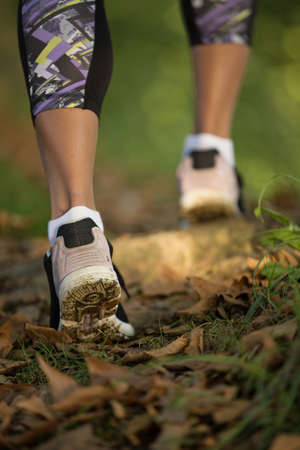 Woman feet in shoes on a forest path on sunset.