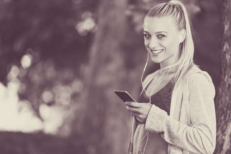 Relaxed fitness woman texting sms on smartphone during a workout break