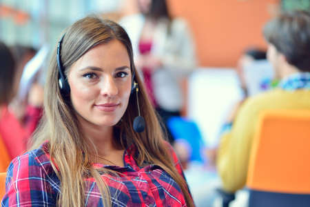 Cute businesswoman in. an office with colleagues at the backgroundの写真素材