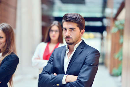 Smilling young business woman in front her team blured in background. Group of young business people. Modern bright startup office interior.の写真素材