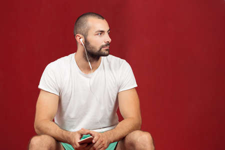 man sitting on a gym ball holding a phone after doing a work out.の写真素材
