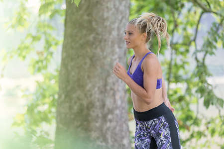 Jogging woman running in park in sunshine on beautiful summer day. Sport fitness model of Caucasian ethnicity training outdoor for marathon.の写真素材
