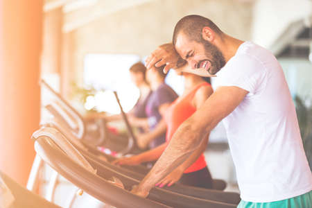Man running in a modern gym on a treadmill concept for exercising, fitness and healthy lifestyleの写真素材