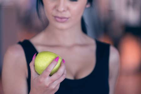 Torso of a woman with a green apple on a dark background.の写真素材