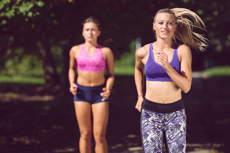 Two athletic woman running outdoors. Action and healthy lifestyle concept