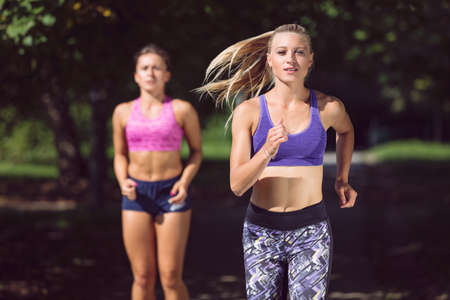 Two athletic woman running outdoors. Action and healthy lifestyle conceptの写真素材