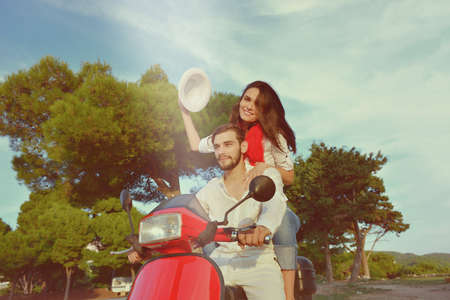 Beautiful young couple in love enjoying and having fun riding on a scooter in a beautiful natureの写真素材