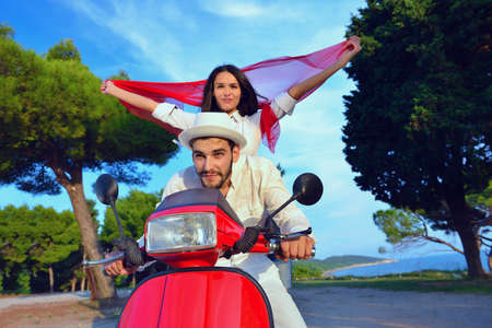 Beautiful young couple in love enjoying and having fun riding on a scooter in a beautiful natureの写真素材