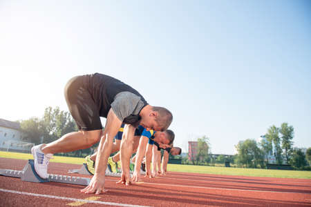 Runners preparing for race at starting blocks.