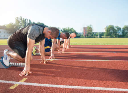 Close-up side view of cropped people ready to race on track field.の写真素材