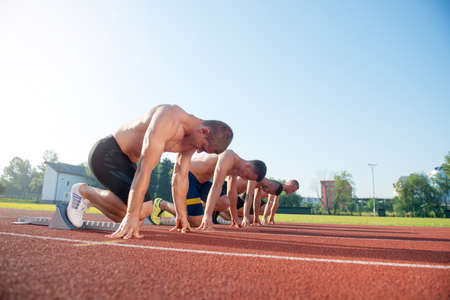 Male athletics runners on starting line without shirtsの写真素材