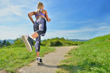 Woman running. Young girl runner jogging on a mountain trail in the beautiful landscape. Healthy...