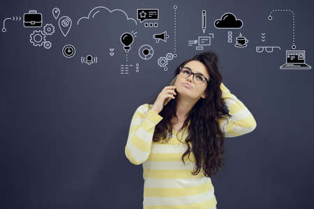 Woman talking on phone in front of background with drawn business charts and symbols