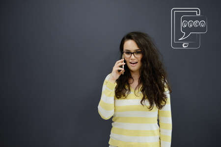 Woman talking on phone in front of background with drawn business charts and symbolsの写真素材