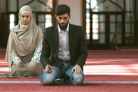 Muslim man and woman praying in mosque.の写真素材