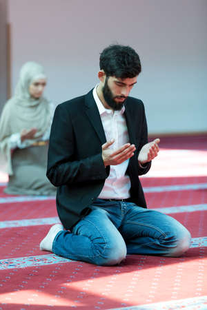 Muslim man and woman praying in mosque.