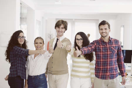 Laughing young business entrepreneurs in informal trendy clothing standing celebrating a successの写真素材