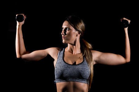 Close-up of a young woman exercising with weights in the gym.の写真素材