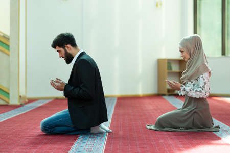 Muslim man and woman praying in mosque.の写真素材