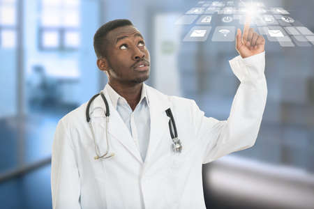 Closeup portrait of black african american doctor with finger at medical symbols. Positive face expression, emotions, feeling, attitudeの写真素材