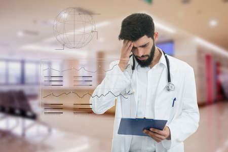 Worried young doctor with head in hand at modern hospital.の写真素材